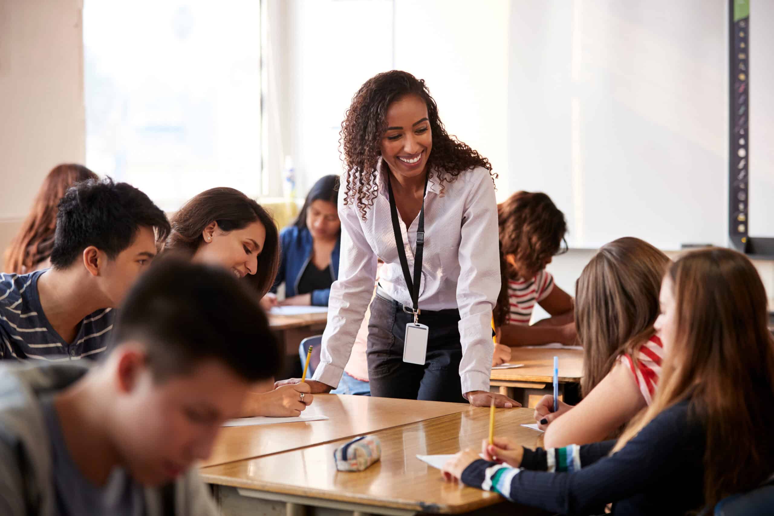 Jeune femme souriante enseignant à un groupe d'élèves en classe, éducation numérique.